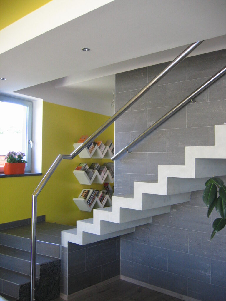 Nerezové schodišťové madlo – lomené, kotvené do podlahy a stěny(interiér, čistá linie, žádné kudrlinky)